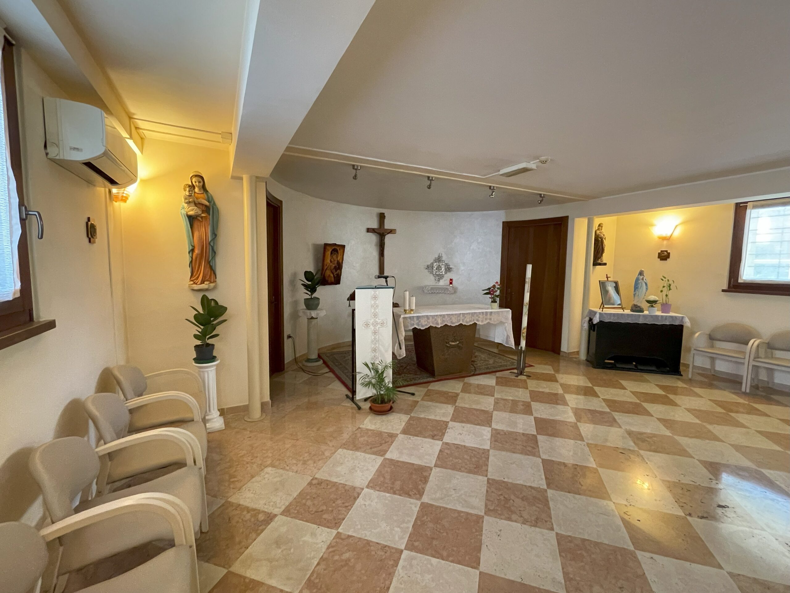 Altare con candele e statua della Madonna, in una stanza semplice e silenziosa