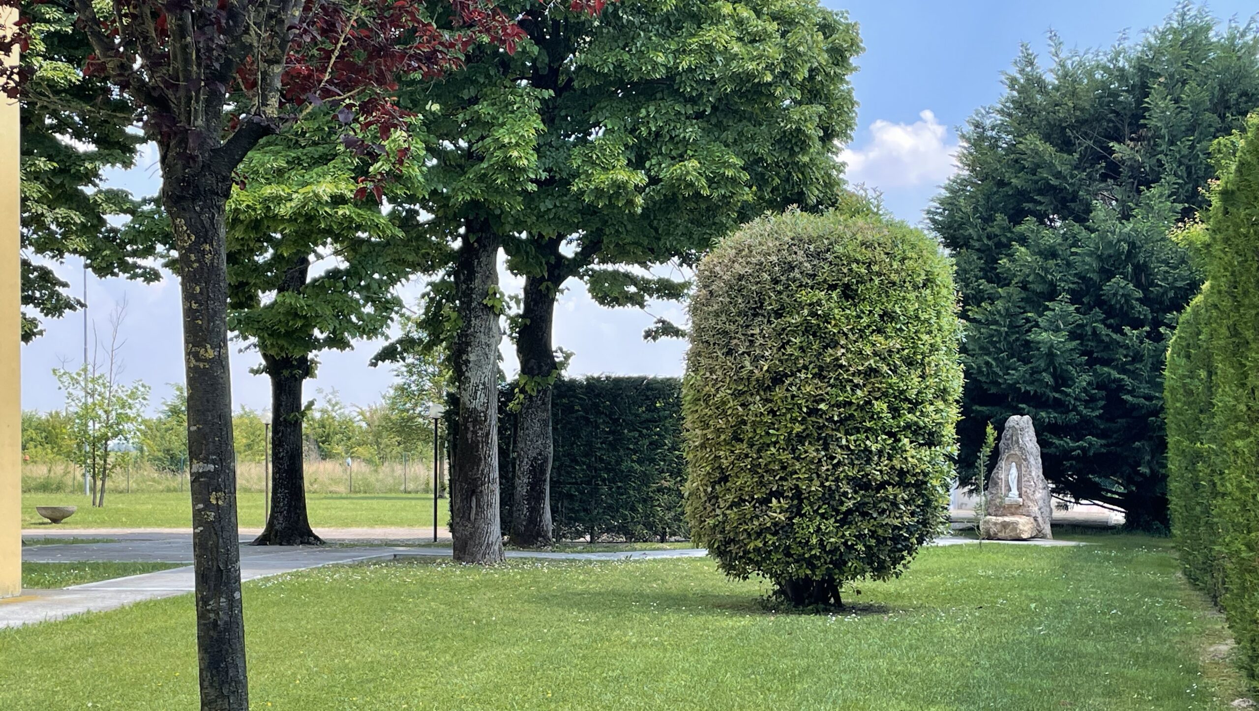 Siepi potate, vialetto in pietra e monumento decorativo in un’area verde tranquilla